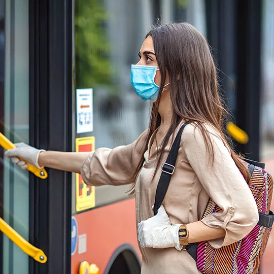 Girl wearing a mask and getting on a bus