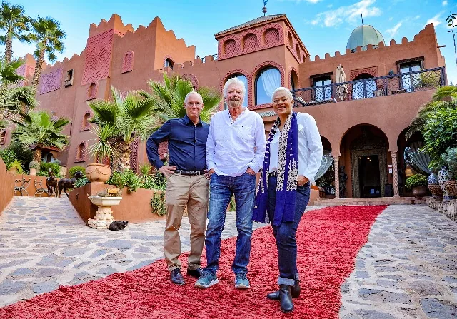 A group of people standing in front of a red carpetDescription automatically generated