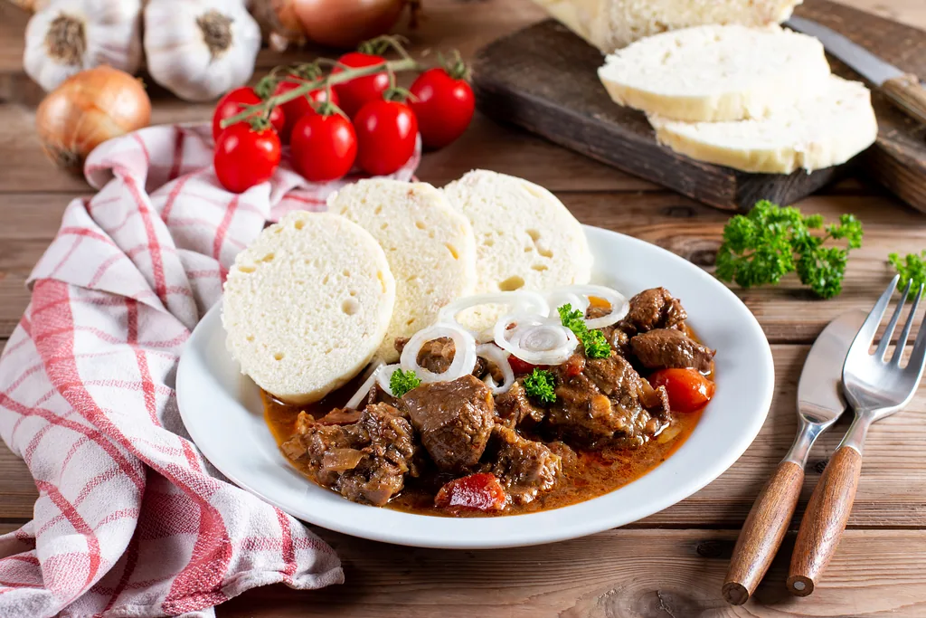 Traditional czech goulash with dumplings on wooden table