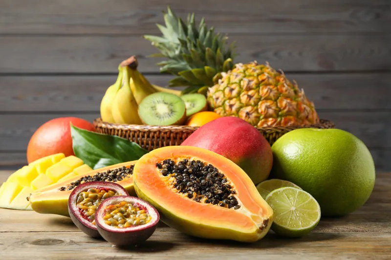Fresh ripe papaya and other fruits on wooden table