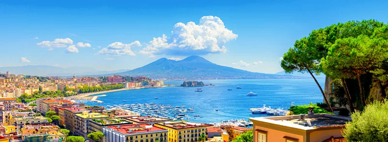 Naples, Italy. View of the Gulf of Naples from the Posillipo hill with Mount Vesuvius far in the background and some pine trees in foreground. Banner header hor