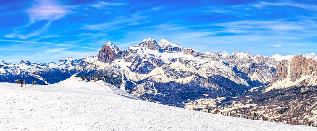 Winter landscape in Dolomites, ski slope with skier in Cortina D'Ampezzo with mountain range in background, image taken from Faloria area