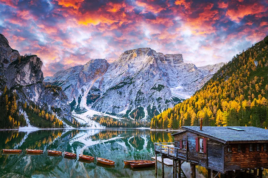 Picturesque landscape with famous lake Braies in autumn Dolomites mountains during incredible sunset. Wooden boats and pier in clear water of Lago di Braies, Do