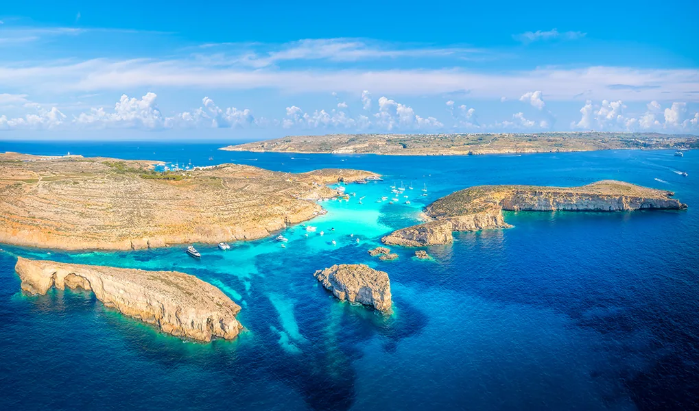 Aerial view of Comino Island, Malta, showcasing the crystal-clear waters and rocky coastline of the Blue Lagoon, perfect for summer adventures and relaxation.