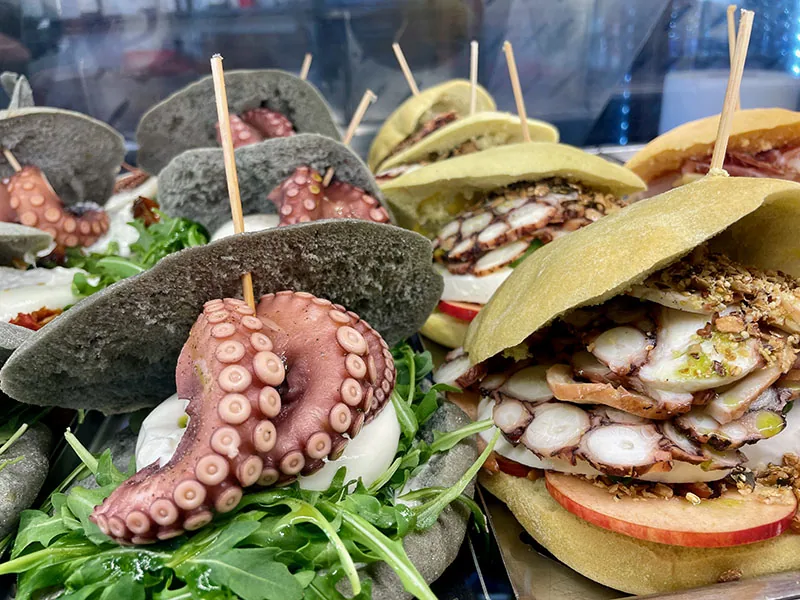 Close up of Puccia sandwiches, bread rolls stuffed with grilled octopus, typical Puglian street food.