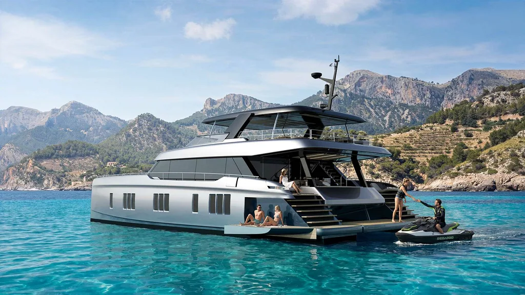 A luxurious Sunreef Yacht anchored in a serene, crystal-clear bay surrounded by rugged mountains. People are relaxing on the aft deck, while someone on a jet sk