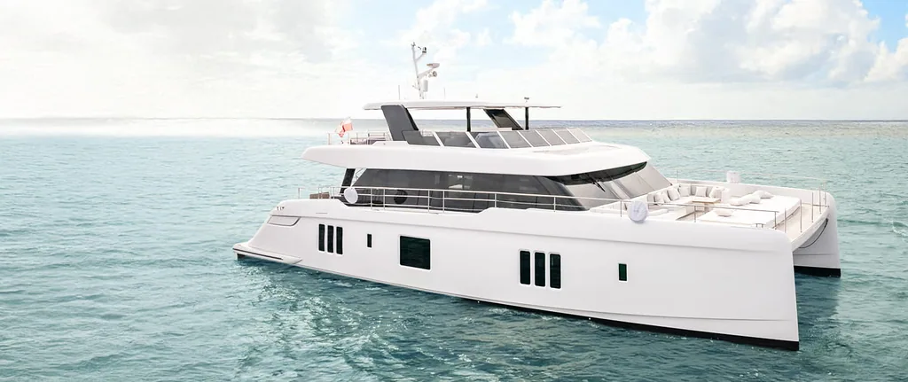 A Sunreef Yachts catamaran is elegantly sailing on calm turquoise waters under a partly cloudy sky.