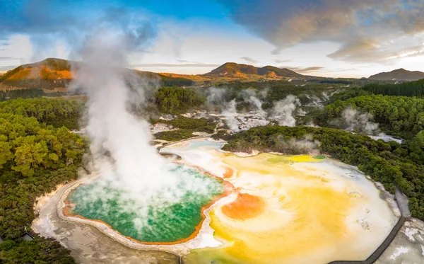 Aerial footage of hot sulphur springs at sunrise, showing colour splashed geothermal reserve of boiling water and steam evaporating in North Island of New Zeala