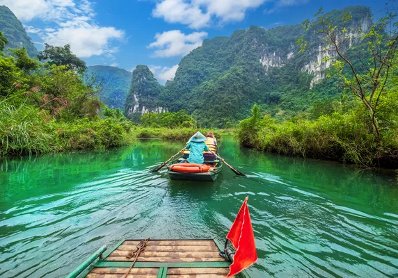 Beautiful landscape view of a touristic and traditional boat sailing through Tràng An karst landscape in Vietnam on a sunny day