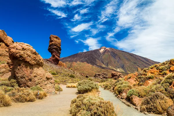 Panoramic view of unique Roque Cinchado unique rock formation with famous Pico del Teide mountain volcano summit in the background on a sunny day, Teide Nationa