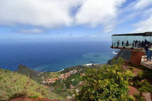 La Gomera, Canary Islands, Spain - April 10, 2018: Unidentified tourists on glass skywalk Mirador de Abrante with view to village Agulo, Atlantic ocean and Teid