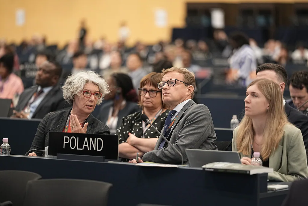 Sesja Komitetu Światowego Dziedzictwa UNESCO, sala konferencyjna, kilka osób przy stoliku z tabliczką "POLAND"
